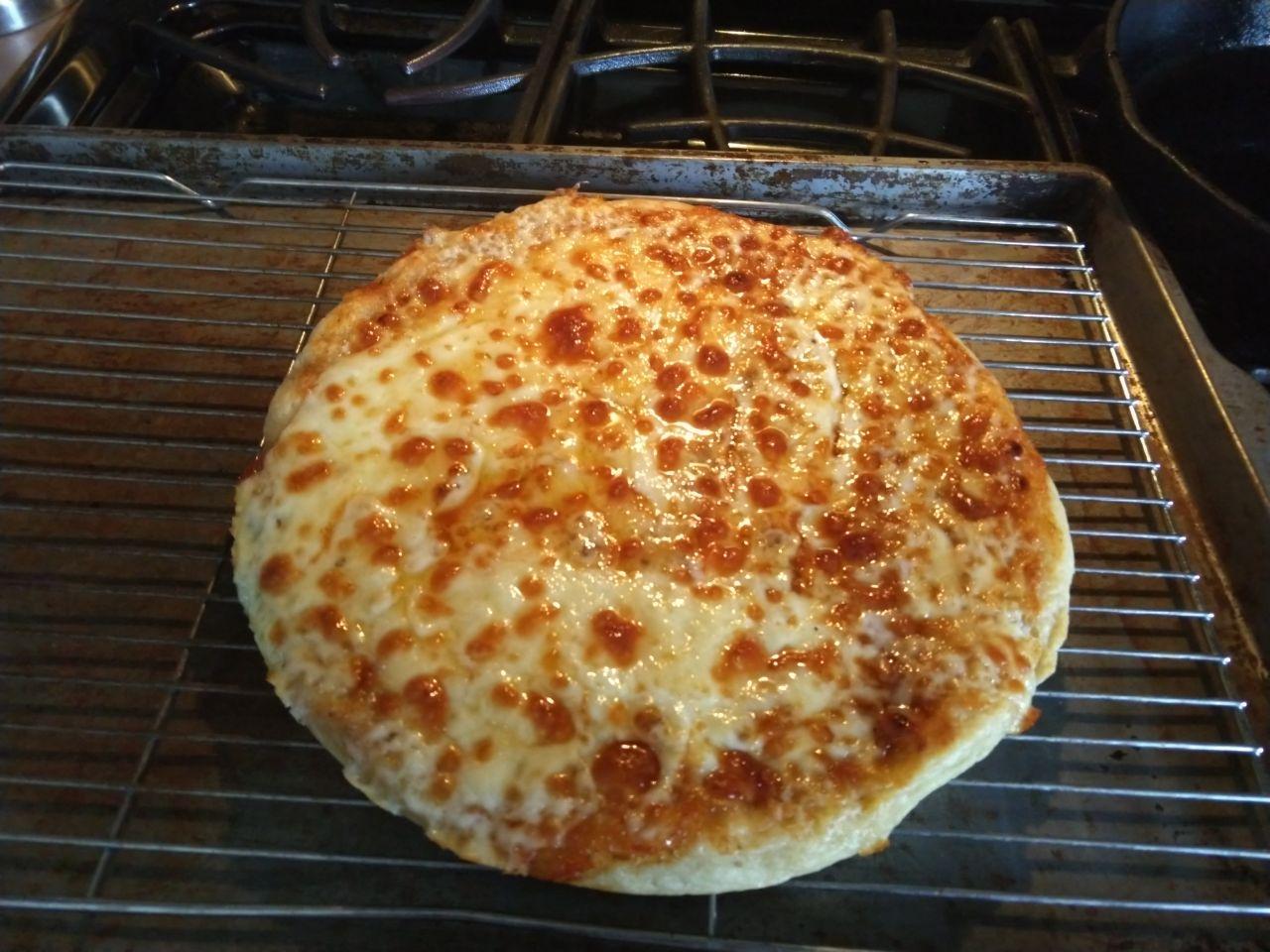 Finished pizza cooling on a rack. Finished pizza cooling on a rack.